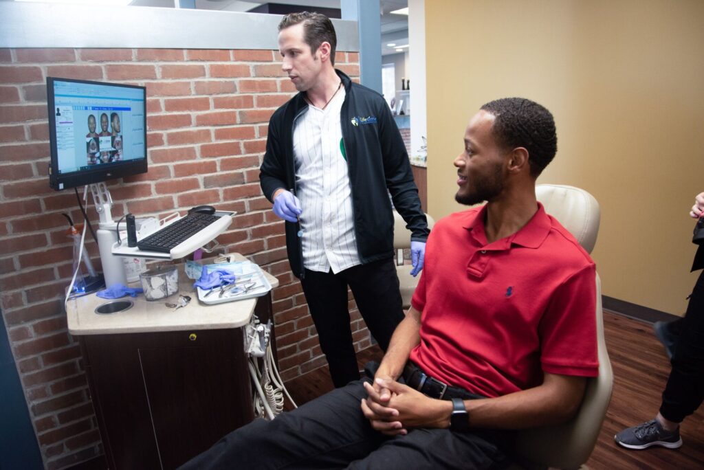 Dr. Gerald Wesley reviews digital orthodontic records on a chairside monitor with an adult patient during a braces consultation at Lifetime Orthodontics in Grosse Pointe Woods and Clinton Township
